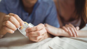 Una pareja abriendo un preservativo
