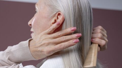 Mujer peinándose su melena canosa