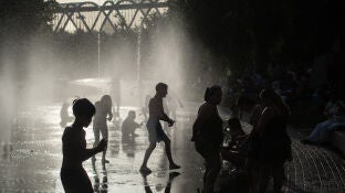 Varias personas se refrescan en las fuentes de Madrid R&iacute;o.