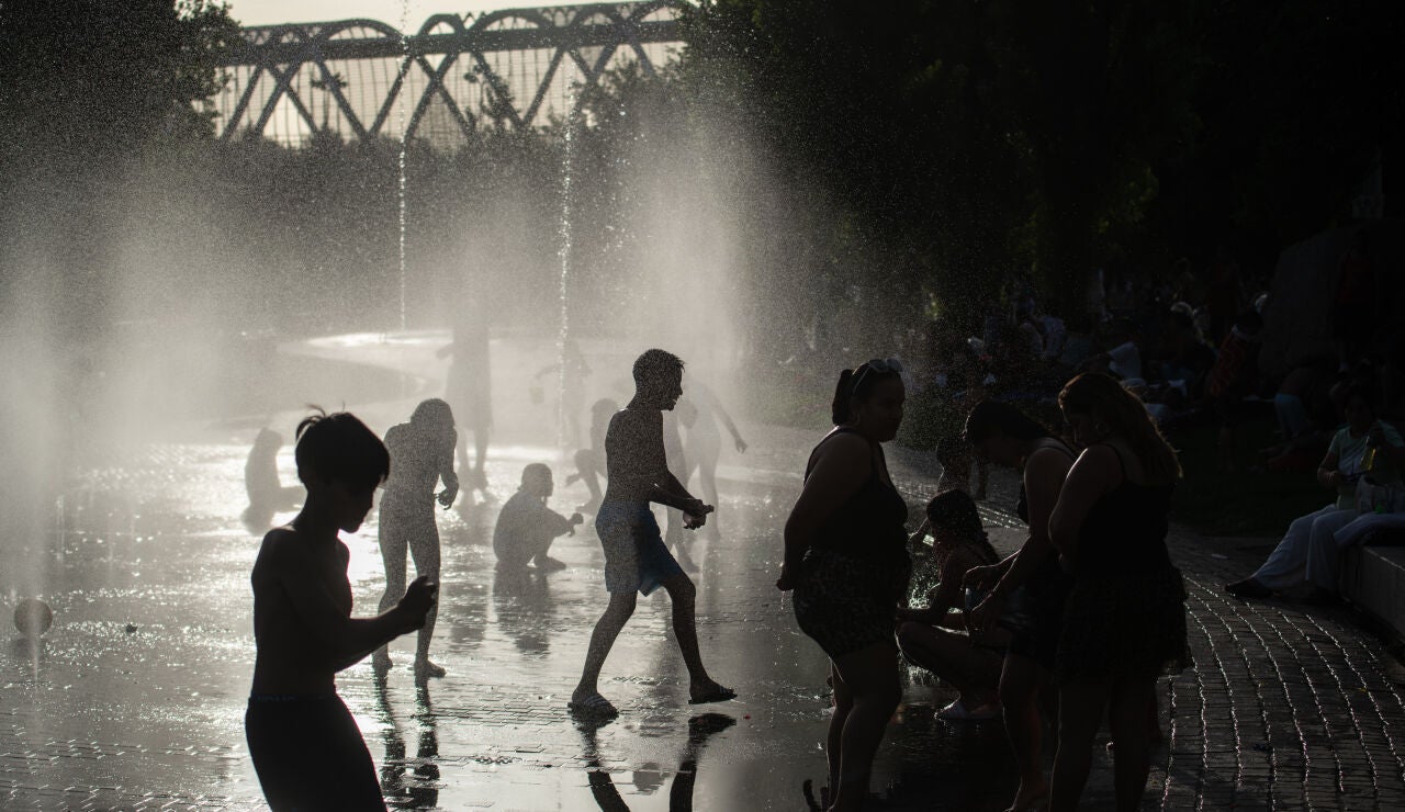 Varias personas se refrescan en las fuentes de Madrid R&iacute;o.