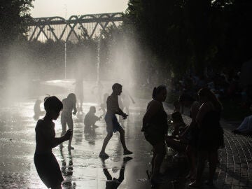 Varias personas se refrescan en las fuentes de Madrid R&iacute;o.