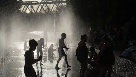 Varias personas se refrescan en las fuentes de Madrid R&iacute;o.