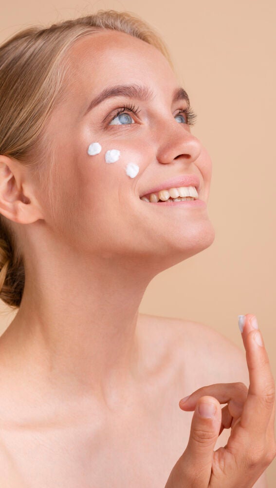 Mujer aplicándose crema solar facial