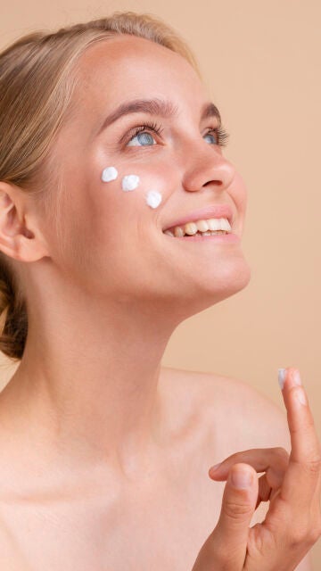 Mujer aplicándose crema solar facial