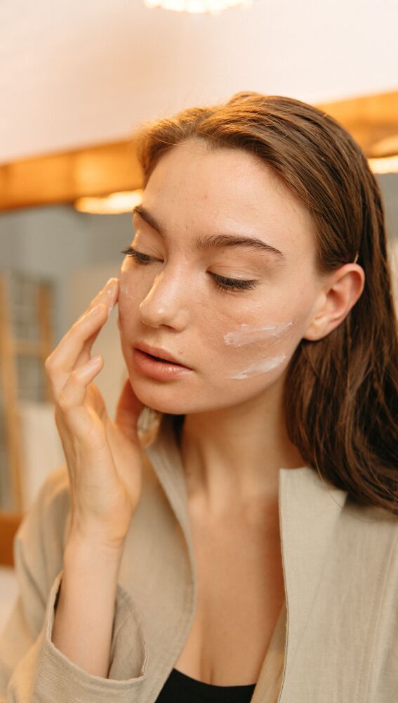 Mujer aplicándose crema solar facial