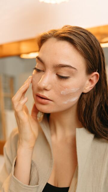 Mujer aplicándose crema solar facial