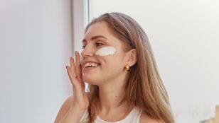 Mujer aplic&aacute;ndose crema solar facial