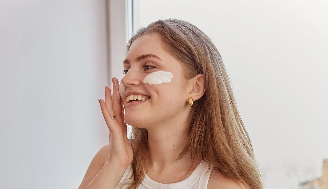 Mujer aplicándose crema solar facial