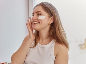 Mujer aplic&aacute;ndose crema solar facial