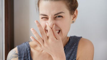 Mujer tap&aacute;ndose la nariz por el mal olor