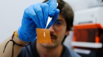 El investigador Yigit Sozen sostiene un chip en un trozo de piel