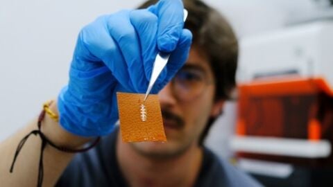 El investigador Yigit Sozen sostiene un chip en un trozo de piel