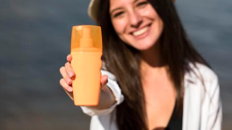 Chica con un bote de protector solar en la mano
