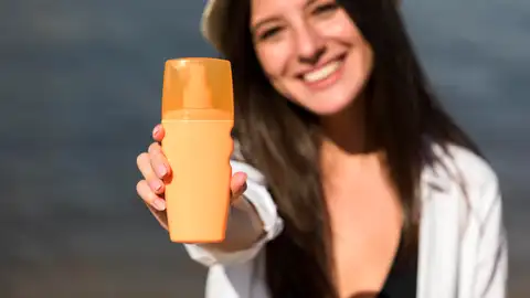 Chica con un bote de protector solar en la mano Chica con un bote de protector solar en la mano