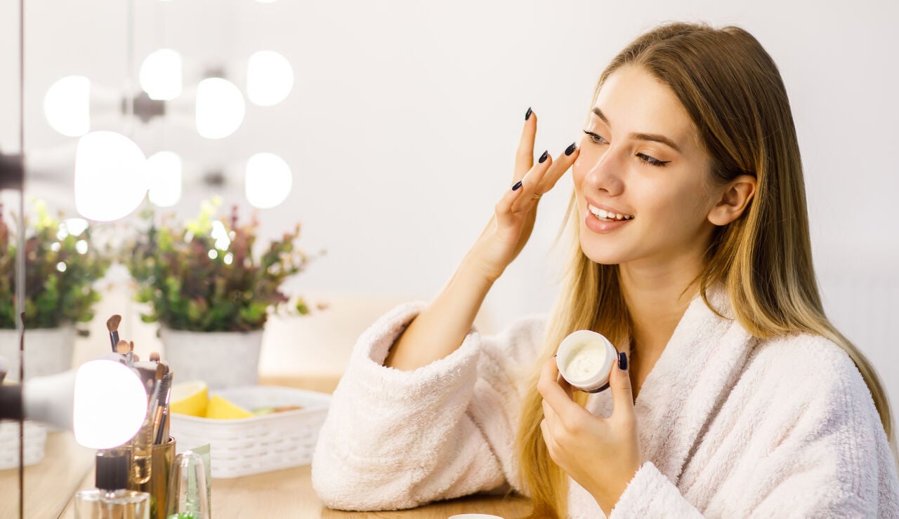 Mujer poni&eacute;ndose cosm&eacute;tico y mir&aacute;ndose al espejo 