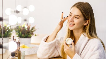 Mujer poni&eacute;ndose cosm&eacute;tico y mir&aacute;ndose al espejo 