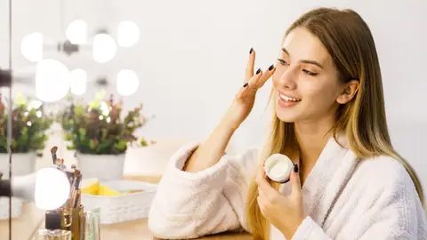 Mujer poniéndose cosmético y mirándose al espejo Mujer poniéndose cosmético y mirándose al espejo