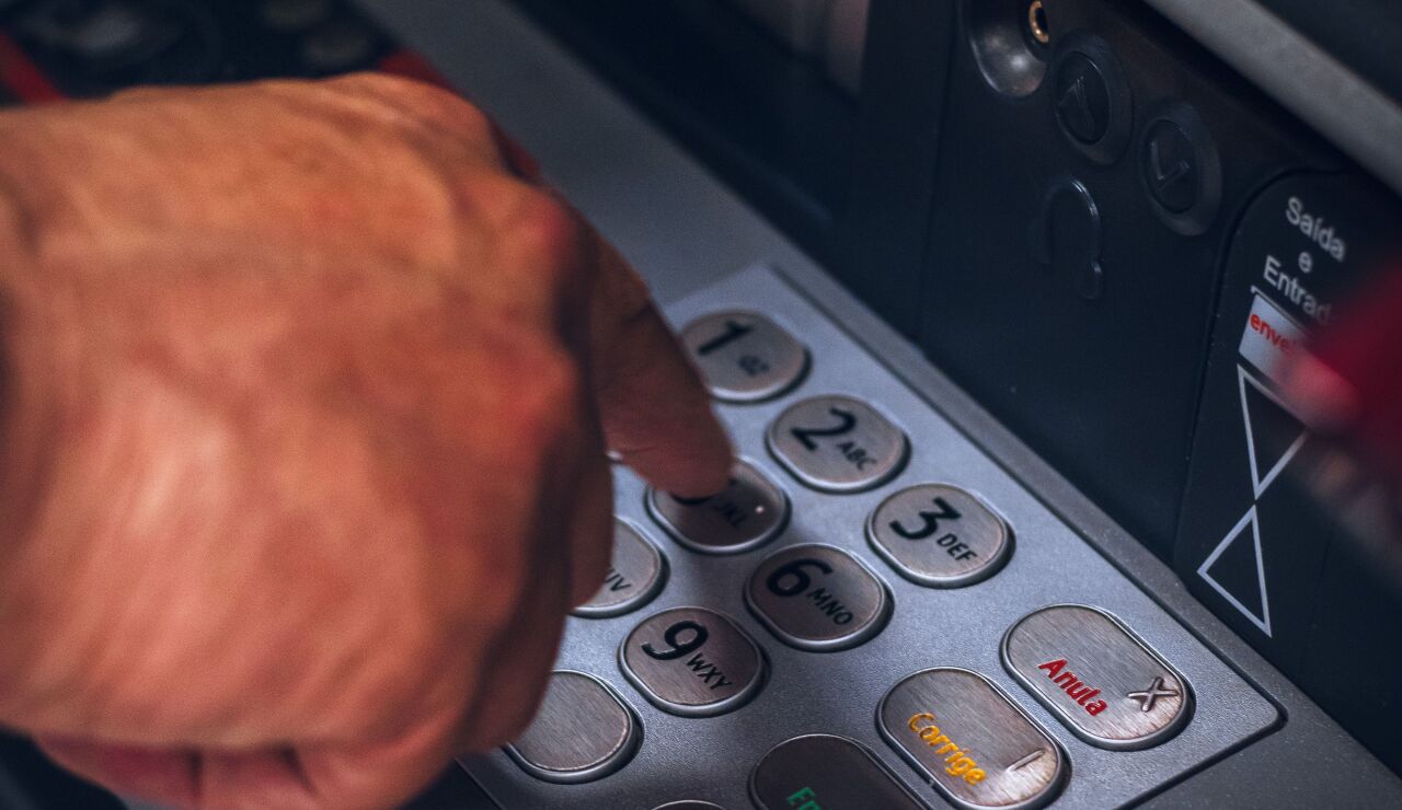 Primer plano de una mano accediendo a un cajero autom&aacute;tico. 