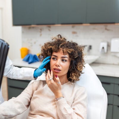Mujer mirando su cara despu&eacute;s de un tratamiento de belleza