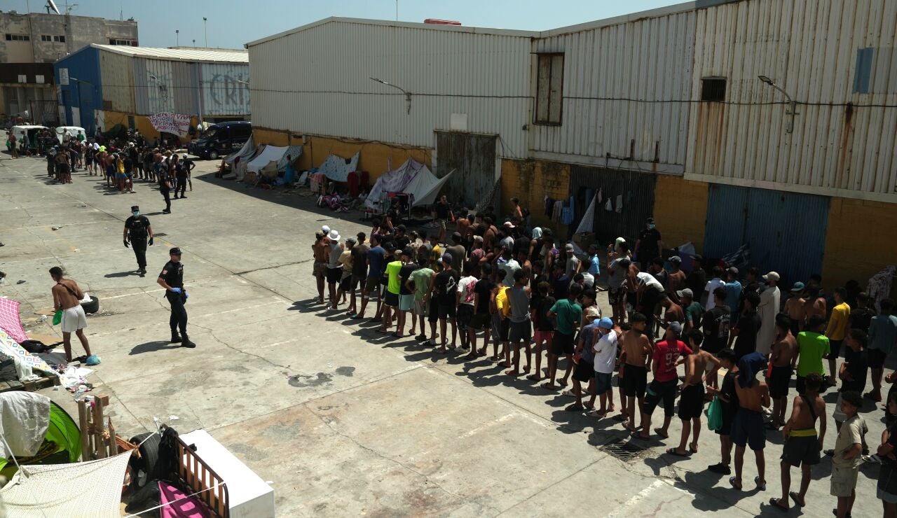 Unos migrantes llegan a un punto de distribuci&oacute;n de alimentos gestionado por Luna Blanca, una ONG con sede en Ceuta.