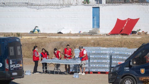Miembros de la Cruz Roja reparten agua a los inmigrantes en una playa, a 21 de agosto de 2026, en Ceuta (Espa&ntilde;a). Ceuta sigue afrontando una grave crisis humanitaria despu&eacute;s de la hist&oacute;rica entrada masiva de m&aacute;s de 70.000 migrantes a nado por el Tarajal durante los d&iacute;as 30 y 31 del pasado mes de julio. Aunque actualmente el despliegue policial y el refuerzo de la frontera por parte de las autoridades marroqu&iacute;es han conseguido frenar las entradas, la ciudad aut&oacute;noma sigue enfrentando una grave...