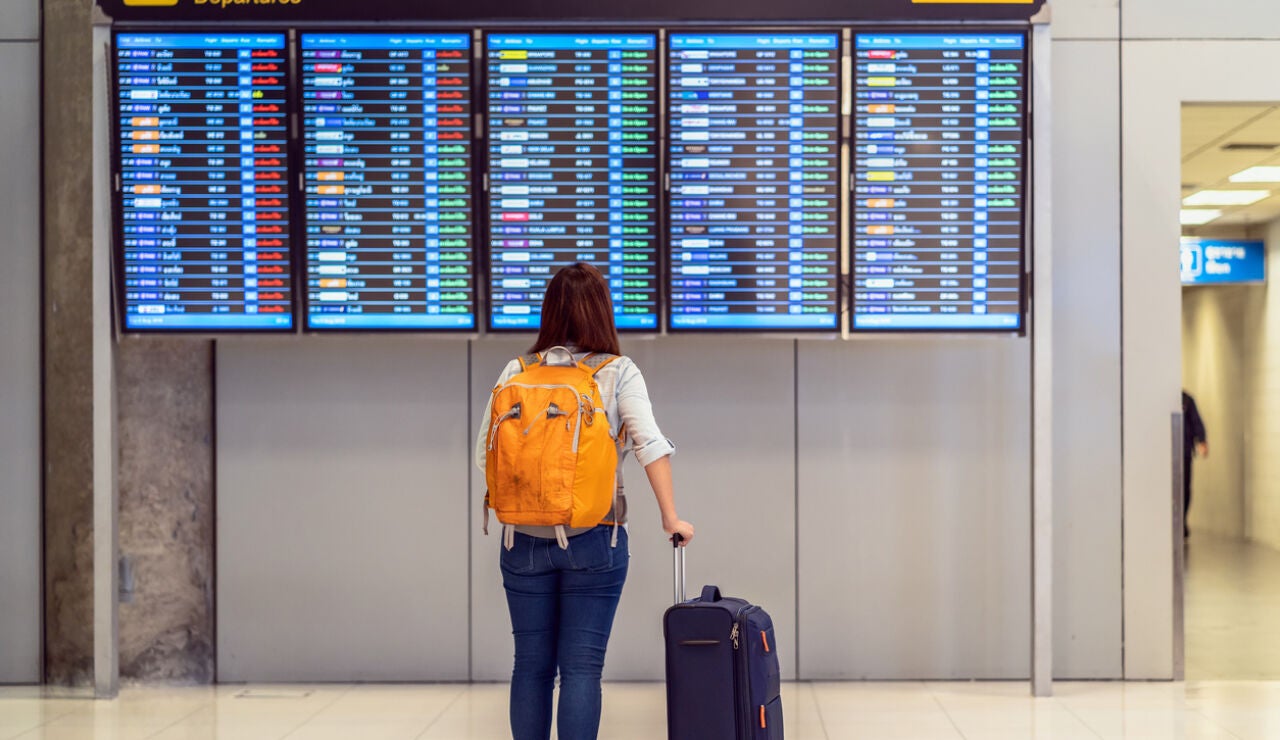 persona mirando panel de salidas aeropuerto