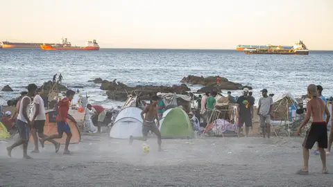 La playa del Trampolín vuelve a presentar el mismo aspecto que durante los primeros días de la llegada masiva de migrantes Decenas de personas viven y pernoctan en la playa del Trampolín, a 28 de agosto de 2026, en Ceuta (España). En la zona de la playa del Trampolín permanecen aún cientos de migrantes en situación irregular, donde han vuelto a construir chozas. 28 AGOSTO 2026 CRISIS MIGRATORIA Marcos Moreno / Europa Press 28/08/2026