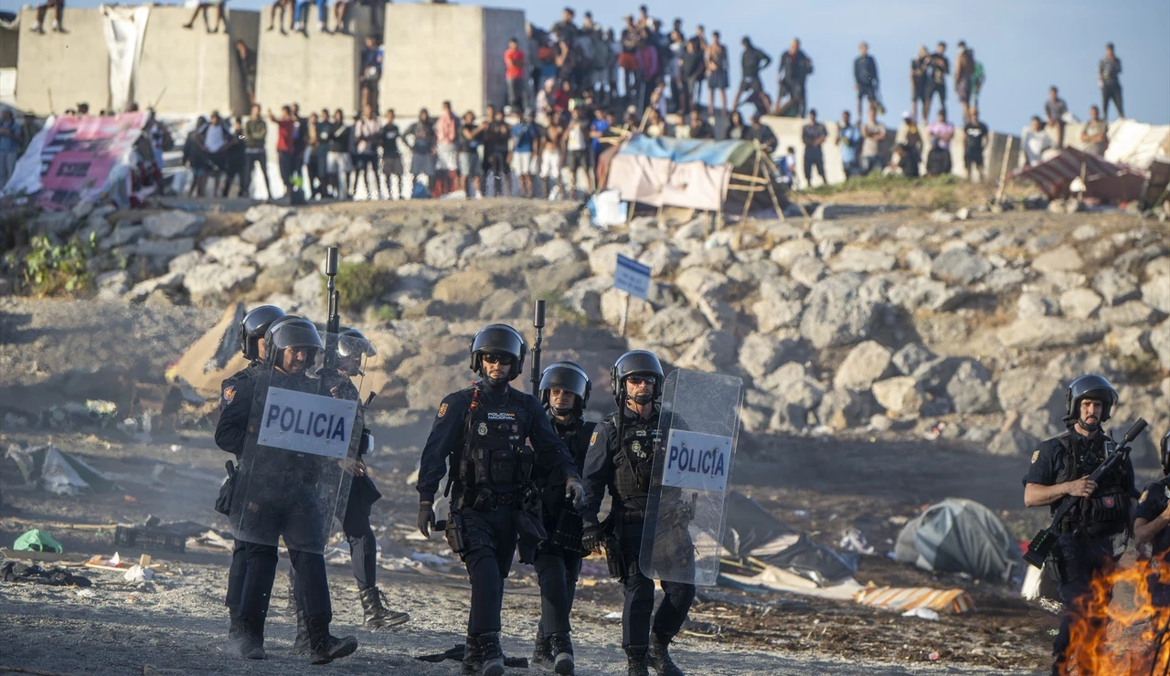 Policías y migrantes en la playa durante una manifestación en Ceuta.