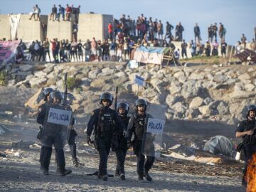 Polic&iacute;as y migrantes en la playa durante una manifestaci&oacute;n en Ceuta.