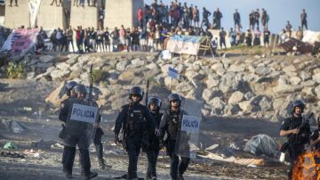 Polic&iacute;as y migrantes en la playa durante una manifestaci&oacute;n en Ceuta.