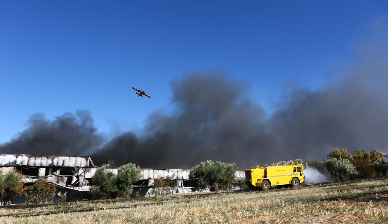 Un helic&oacute;ptero de extinci&oacute;n de incendios sobrevuela una densa columna de humo negro durante las labores para sofocar el incendio provocado por el accidente de un avi&oacute;n de combate F-4 Phantom de la Fuerza A&eacute;rea Hel&eacute;nica