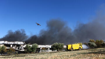 Un helic&oacute;ptero de extinci&oacute;n de incendios sobrevuela una densa columna de humo negro durante las labores para sofocar el incendio provocado por el accidente de un avi&oacute;n de combate F-4 Phantom de la Fuerza A&eacute;rea Hel&eacute;nica