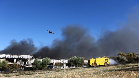 Un helic&oacute;ptero de extinci&oacute;n de incendios sobrevuela una densa columna de humo negro durante las labores para sofocar el incendio provocado por el accidente de un avi&oacute;n de combate F-4 Phantom de la Fuerza A&eacute;rea Hel&eacute;nica