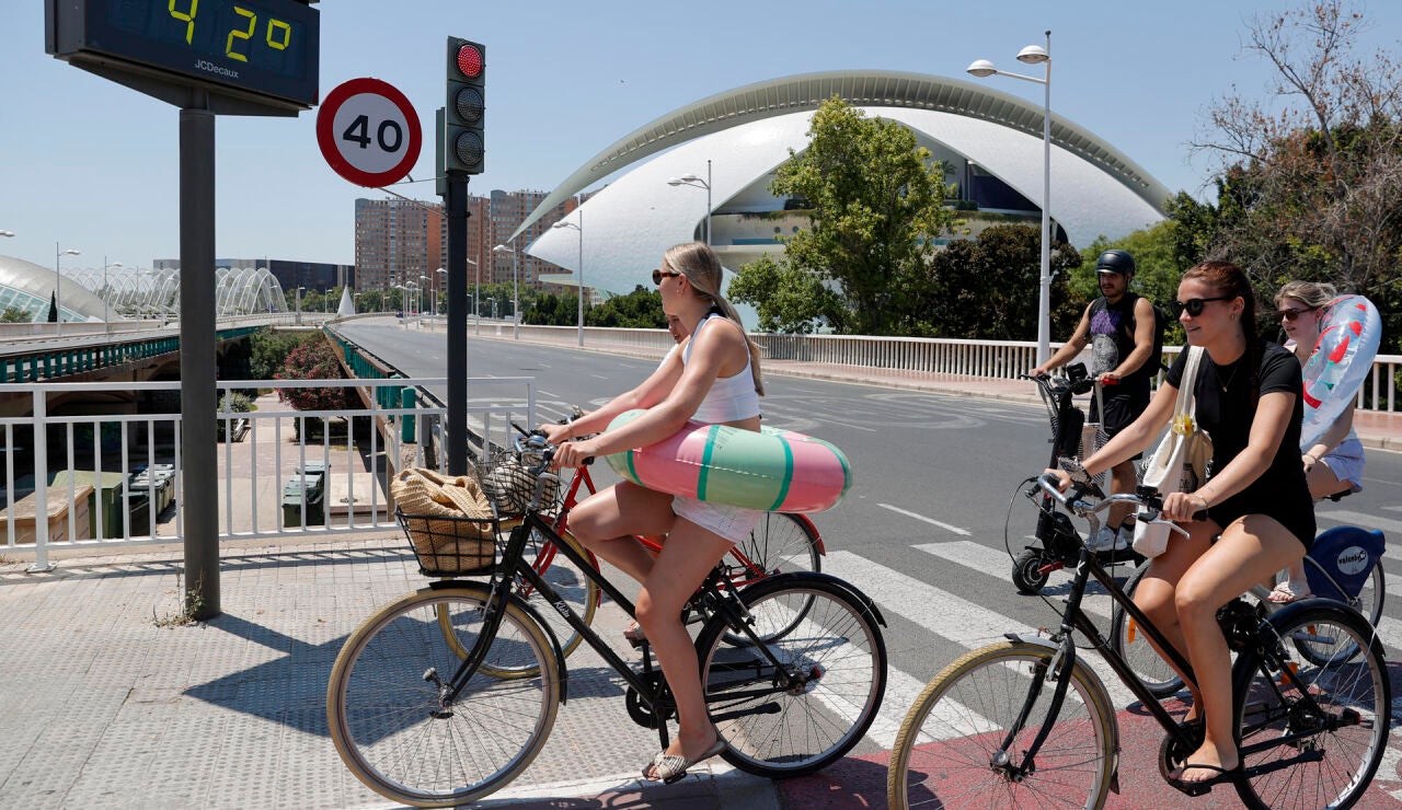 Varias j&oacute;venes transportan sus flotadores en bici