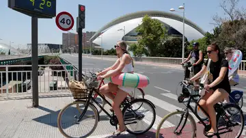 Varias jóvenes transportan sus flotadores en bici Varias jóvenes transportan sus flotadores en bici