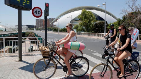 Varias j&oacute;venes transportan sus flotadores en bici