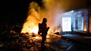 Un bombero frente a una barrica en llamas en Par&iacute;s