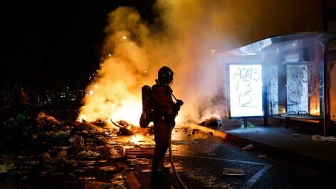 Un bombero frente a una barrica en llamas en Par&iacute;s