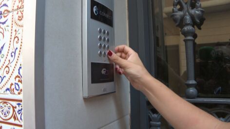 Una mujer tocando el telefonillo de una vivienda