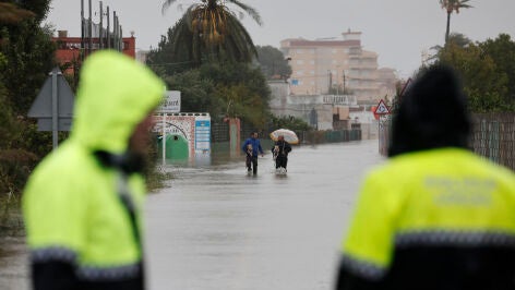  Dos residentes abandonan la playa de Bellreguard (Valencia) por una calzada inundada este lunes