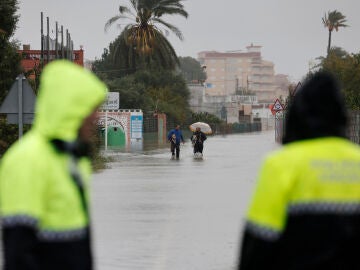  Dos residentes abandonan la playa de Bellreguard (Valencia) por una calzada inundada este lunes por la DANA Adam